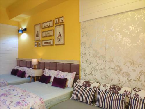 a bedroom with two beds and a wall with paintings at Teacher Cai Homeestay in Xiaoliuqiu