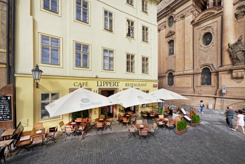an outdoor cafe with tables and chairs and umbrellas at Hotel Lippert in Prague
