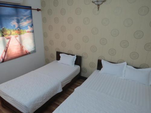two white beds in a room with a picture on the wall at KHÁCH SẠN HƯƠNG SEN PHÚ YÊN in Tuy Hoa