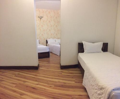 a room with two beds and a wooden floor at KHÁCH SẠN HƯƠNG SEN PHÚ YÊN in Tuy Hoa