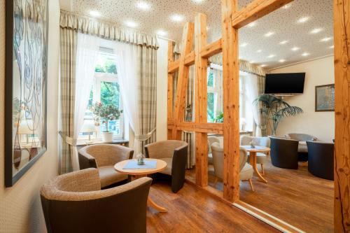 a salon with chairs and tables and a mirror at Comfort Hotel Am Kurpark GmbH in Bad Homburg vor der Höhe