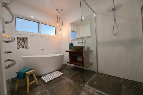 a bathroom with a tub and a glass shower at Sawtell Beach Shack 1 in Sawtell