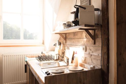 um balcão de cozinha com um lavatório e uma janela em moments café & apartmenthaus em Thurnau