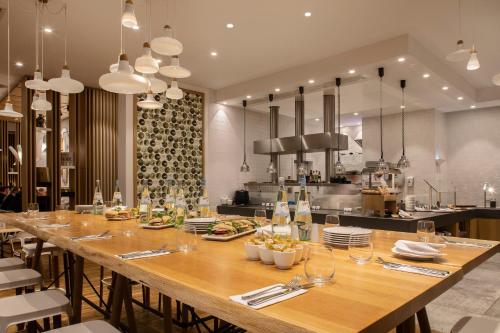 a large wooden table in a restaurant with a kitchen at Holiday Inn Frankfurt - Alte Oper by IHG in Frankfurt/Main