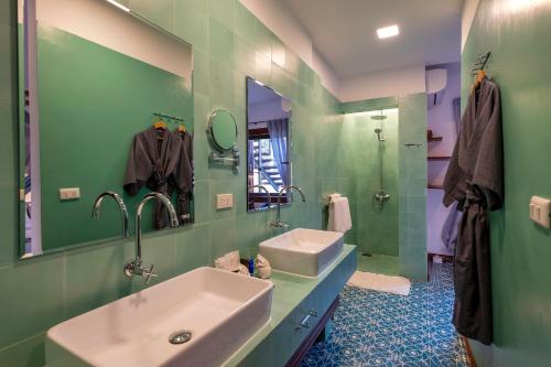 Baño verde con lavabo y espejo en Residence Bassac, en Champasak