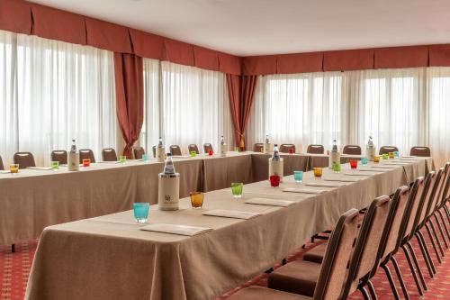 a row of long tables in a room with chairs at Hotel Ambasciatori in Brescia