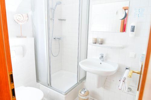 a white bathroom with a shower and a sink at Gästehaus Engelgasse Herzogenaurach in Herzogenaurach