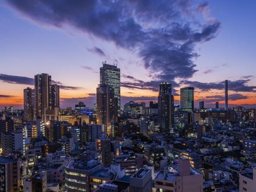 東京にあるアパホテル〈山手大塚駅タワー〉の高層ビルが立ち並ぶ夕日の街並み