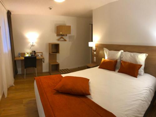 een slaapkamer met een groot wit bed met oranje kussens bij Kyriad Quimper Sud in Quimper