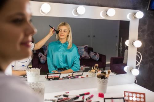 a woman in front of a mirror brushing her hair at Hotel Park Doboj in Doboj
