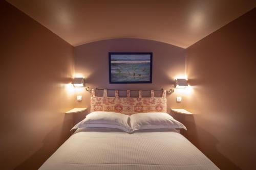 Un dormitorio con una cama con dos luces. en Relais Hôtelier Douce France en Veules-les-Roses
