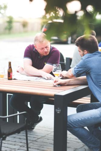 two men sitting at a table with a glass of wine at B&B Nieuwhof in Gistel