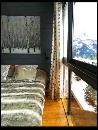 une chambre avec un lit et une grande fenêtre dans l'établissement Appartement T4 esprit chalet jolie vue PRA LOUP 1600, à Pra-Loup