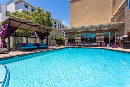 a swimming pool with chairs and an umbrella at Holiday Inn Express & Suites Anaheim Resort Area, an IHG Hotel in Anaheim