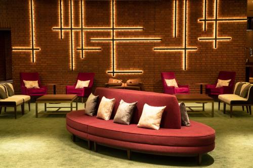 a red couch in a room with chairs and chandeliers at Art Hotel Morioka in Morioka