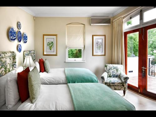 a bedroom with two beds and a chair at 10 Villefranche in Franschhoek