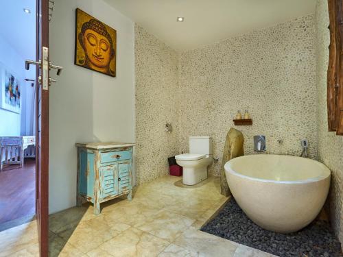 a bathroom with a bath tub and a toilet at Villa Mimpi Manis infinity pool&180°Ocean view in Amed