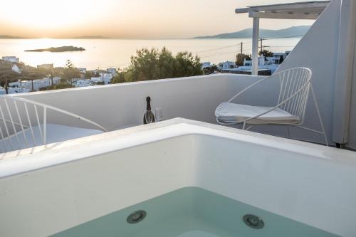 a bath tub on a balcony with a chair at Ostraco Suites in Mikonos