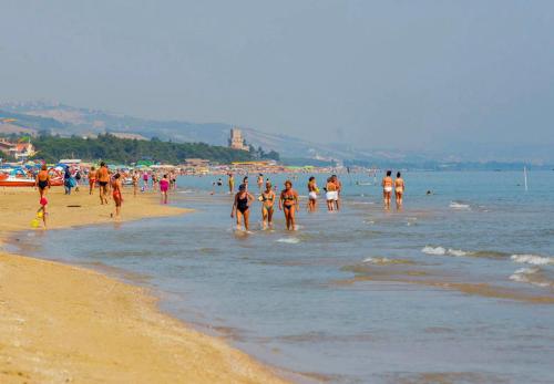 a group of people walking in the water on a beach at La Lanterna in Silvi Marina