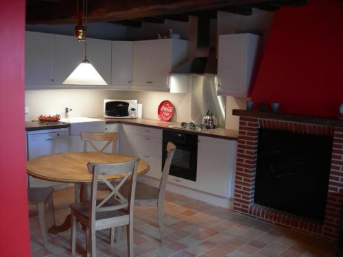 a kitchen with a table and chairs and a fireplace at Gîte La Penhatière in Baulon