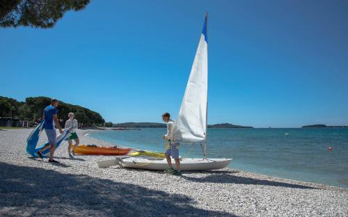 a group of people on a beach with a sailboat at Mobile Homes Bi Village - Adriatic Kampovi in Fažana