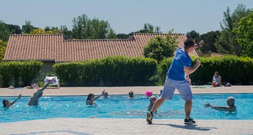 a man playing with a frisbee in a swimming pool at Mobile Homes Bi Village - Adriatic Kampovi in Fažana