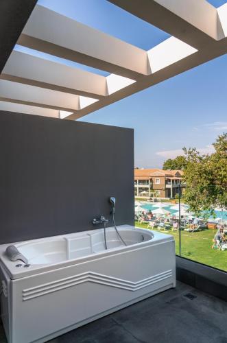 a white bath tub in a room with a window at Acharavi Beach Hotel in Acharavi