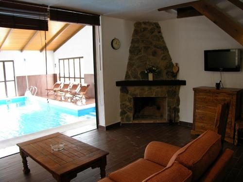 a living room with a fireplace and a swimming pool at casa las serijuelas in Villanueva de Ávila