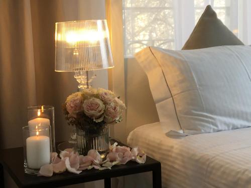 a table with a lamp and a vase of flowers and candles at Villa Liberty in Como