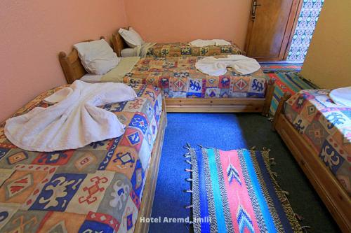 a room with three beds and a blue carpet at Hotel Igoudar Armed in Imlil