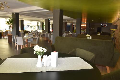 a table with vases of flowers on a table in a restaurant at Hotel Bulevard in Râmnicu Vâlcea