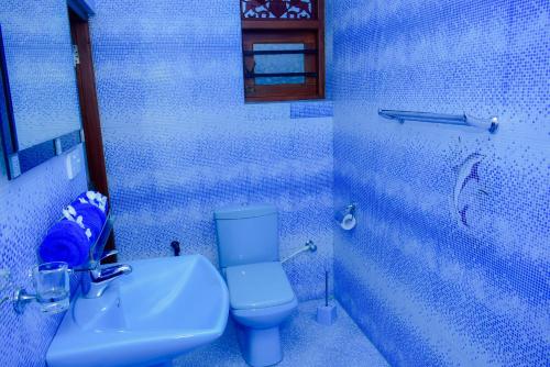 uma casa de banho azul com um WC e um lavatório em Felicia Villa em Hikkaduwa
