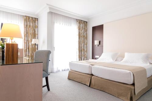 a hotel room with a large bed and a desk at GPRO Valparaiso Palace & Spa in Palma de Mallorca