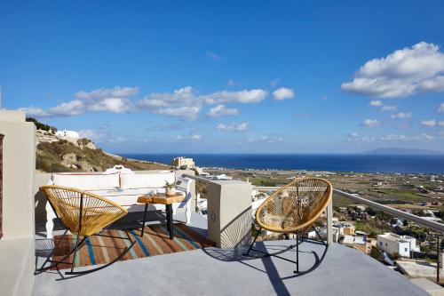 a balcony with chairs and a table and the ocean at Nano Suites in Éxo Goniá