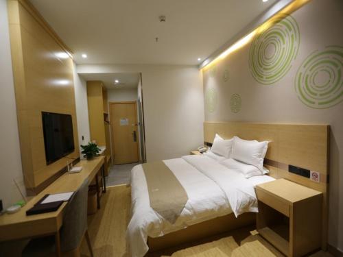 a hotel room with a large bed and a television at GreenTree Inn Dezhou Bus Station Train Station Express Hotel in Dezhou