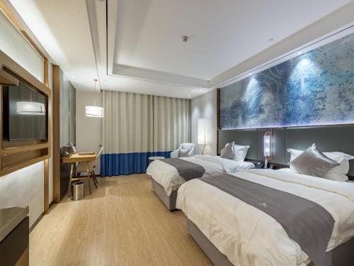 a hotel room with two beds and a flat screen tv at GYA Xuzhou High Speed Railway Station West Exit Station Hotel in Xuzhou