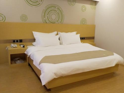 a bedroom with a large bed with white sheets and pillows at GreenTree Inn HuaiAn Area for development Shenzhen East Road Express Hotel in Huai'an