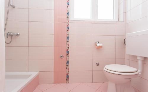 uma casa de banho com um WC e um chuveiro com uma janela em Apartments Vola em Vrbnik