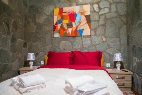 a bedroom with a bed with red pillows and a painting at Konaki inn in Palaios Agios Athanasios