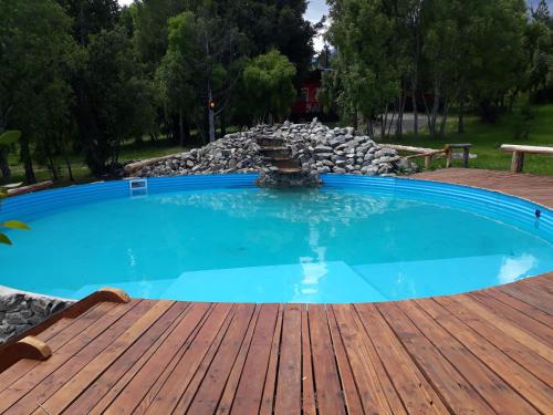 een zwembad op een houten terras met een fontein bij Del Viejo Camino in El Bolsón