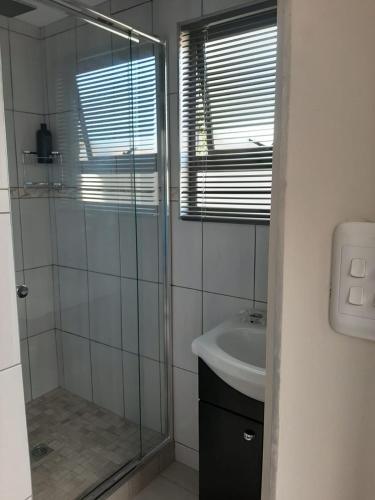 a bathroom with a glass shower and a sink at Vogel's Nest in George