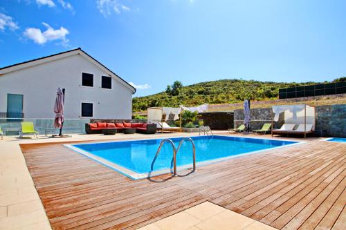 a swimming pool with a wooden deck next to a house at Apartments Kula in Janjina