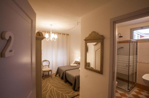 een slaapkamer met een bed, een spiegel en een stoel bij City Garden Guest House in Olbia