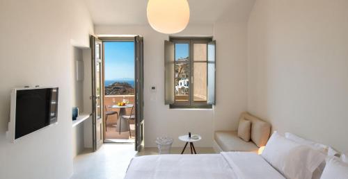 a bedroom with a bed and a couch and a tv at Old Castle Oia in Oia