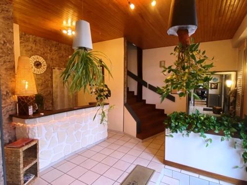 a lobby with a staircase and plants on the wall at Hôtel des Chazes in Saint-Jacques-des-Blats