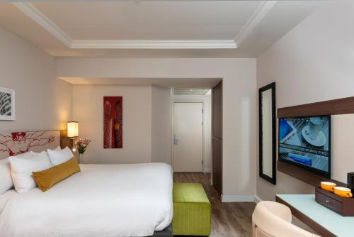 a hotel room with a bed and a tv at Leonardo City Tower Hotel Tel Aviv in Tel Aviv