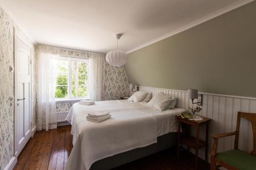 a bedroom with a bed with white sheets and a window at Strandvillan Ljugarn in Ljugarn