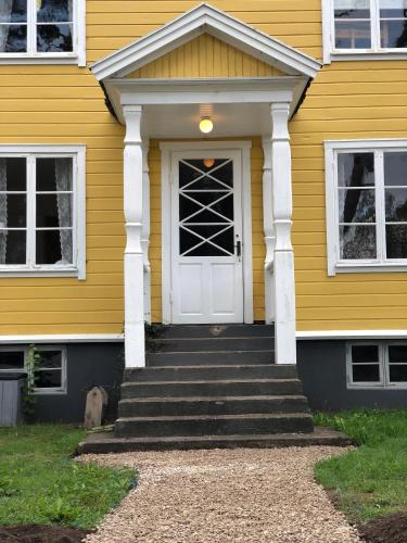 a yellow house with a white door and stairs at Strandvillan Ljugarn in Ljugarn