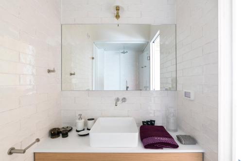 a white bathroom with a sink and a mirror at Andromeda Hill Amazing Suite in Tel Aviv