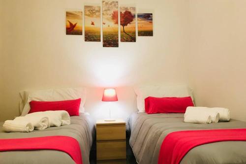 - une chambre avec 2 lits dotés de draps rouges et blancs dans l'établissement Torre San Giovanni, my cozy place..., à Potenza